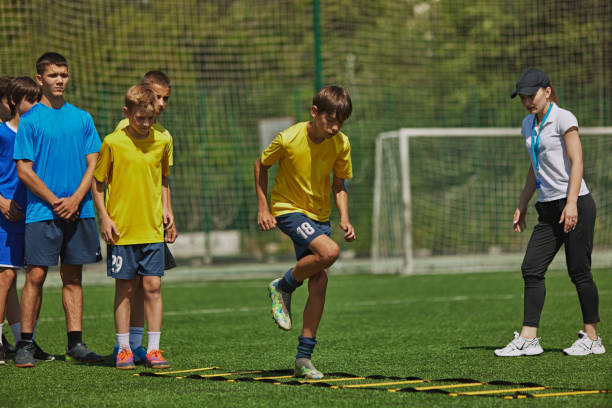 istock Dynamic Soccer Drill. Young soccer players, boys in uniform training outdoors with coach, doing exercises with agility ladder. 2178851555