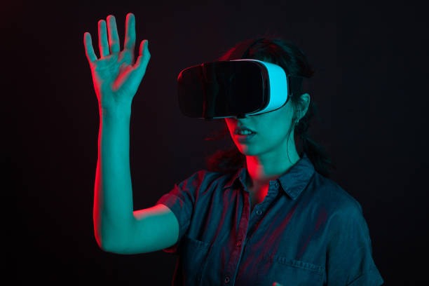 istock Beautiful caucasian young woman playing games using virtual reality helmet in studio with creative lighting 2178856275