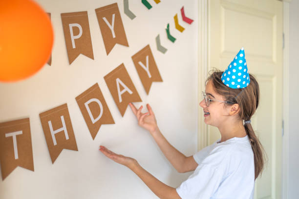istock A girl hangs a happy birthday sign on the wall. Birthday concept. 2178863243