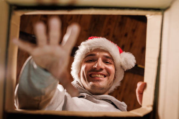 istock Happy man in Santa hat reaches inside gift box 2178866270