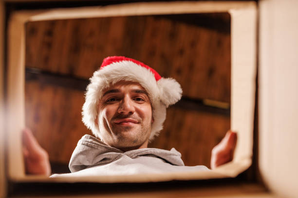 istock Happy man in Santa hat reaches inside gift box 2178866309