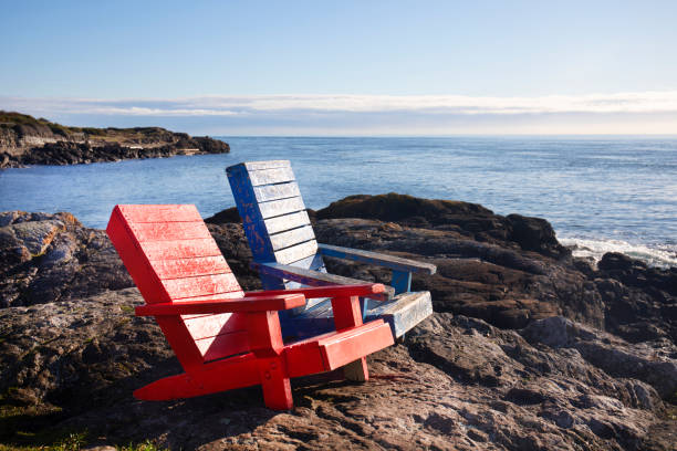 istock two colourful lawn chairs looking out to sea. 2178868717
