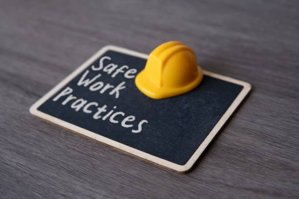 Small chalkboard with the text Safe Work Practices and yellow hard hat.
