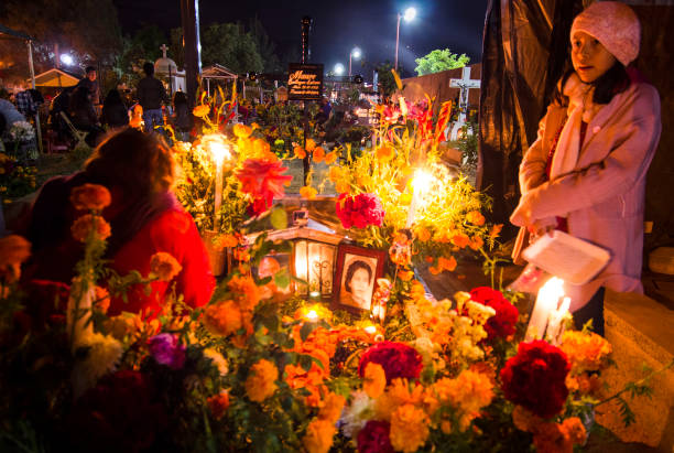 Family members around a grave decorated for the Day of the Dead at the Santa Cruz Xoxocotlán Cemetery in Oaxaca, Mexico.