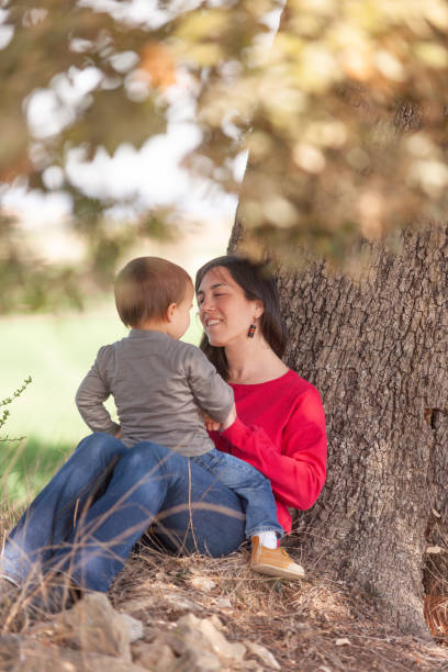 A woman and a child are sitting under a tree