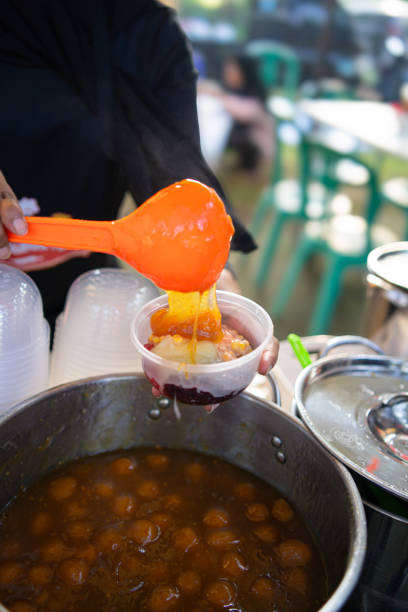 Street vendors pour bubur candil into plastic bowls