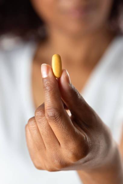 istock Holding a Yellow Capsule Pill Between Fingers 2178912274