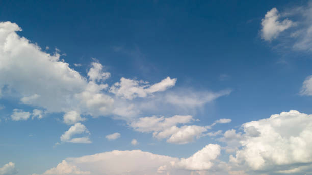 A clear blue sky with fluffy white clouds creates a serene and peaceful atmosphere. Ideal for backgrounds or nature-related themes.