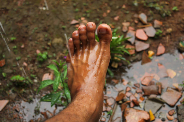 brown skinned man's feet wet from rain splashes