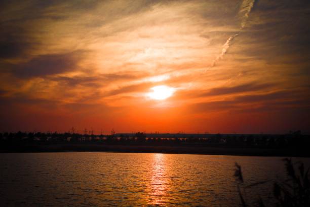 Sunset over a lake with a beautiful orange sky and clouds reflecting on the water