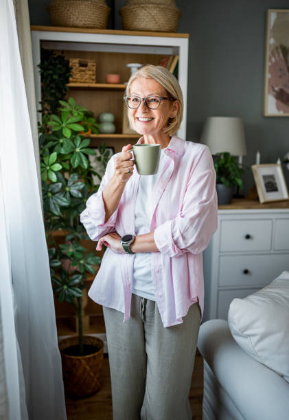 istock Woman with coffee looking through the window 2178948341
