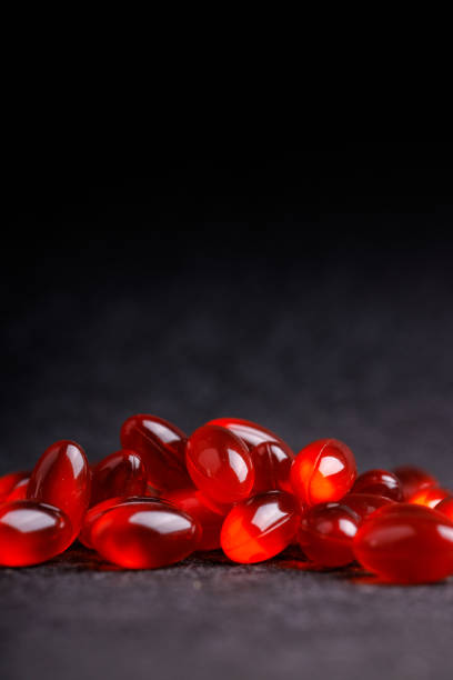 istock Group of glossy red transparent pills displayed on a black surface, emphasizing their rich color and unique shapes in a striking close-up image 2178950621