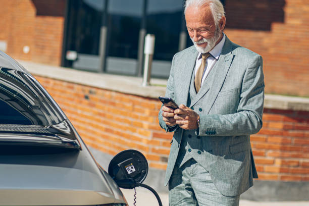 istock Senior Man charging electric car at charging station using smart phone app 2178957109
