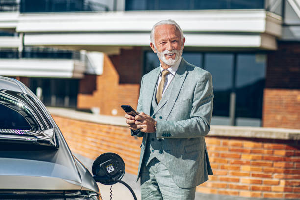 istock Senior Man charging electric car at charging station using smart phone app 2178957802