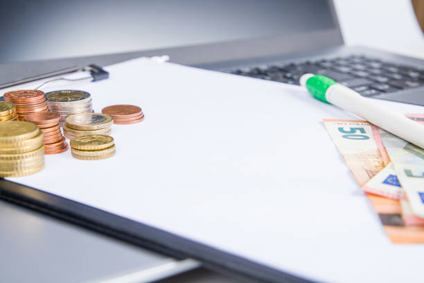 Coins on the table with notebook and pen. Business concept.