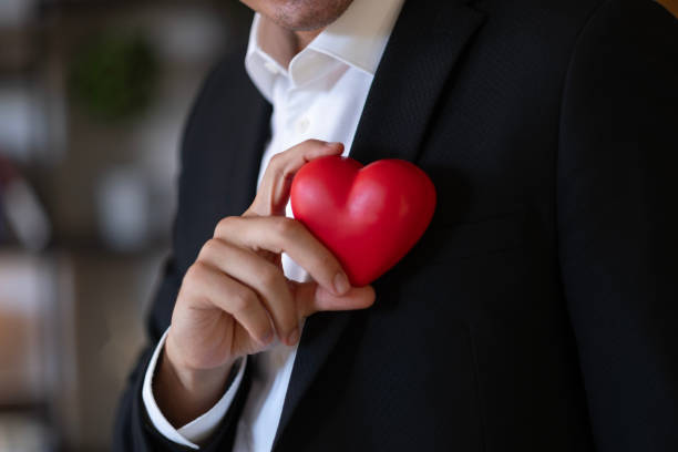 istock The man in a black suit holds the red heart -shaped object. 2178963852