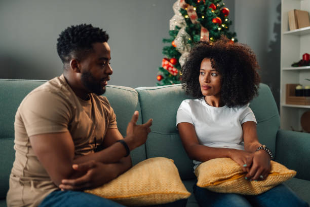 Diverse couple having intense conversation amid festive Christmas tree setting