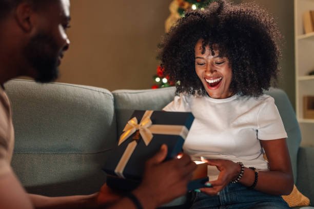 Multiracial couple cherishing a gift exchange moment under Christmas tree