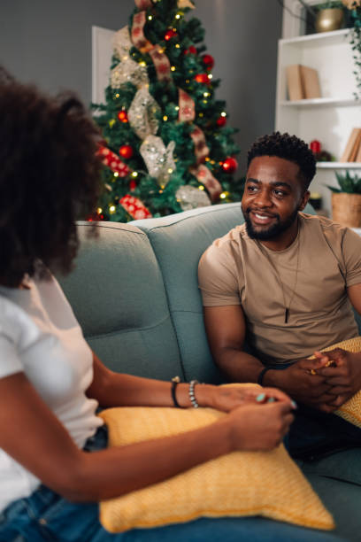 istock Joyful african american pair chatting on sofa by festive Christmas tree 2179008710