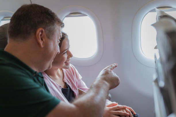 istock Man pointing through the plane window and his daughter following 2179023518