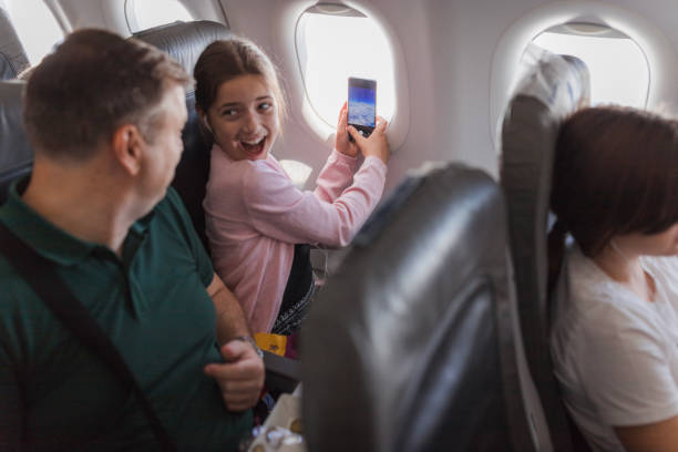 istock Happy girl taking photos through airplane window 2179023578
