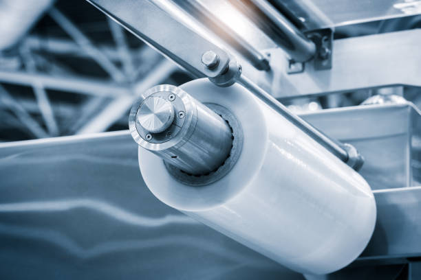 istock Automatic polyethylene plastic bag production machine with lighting effect. Close-up of the roller of the plastic bag production machine in the light blue scene. industrial product packaging concept background 2179025596