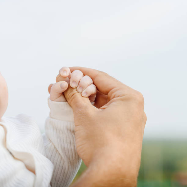 man hand holds little child hand, family care, fatherhood, paternity, cropped, unrecognizable