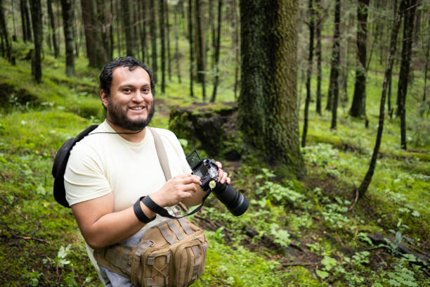 istock Young Mexican man holding a camera in the forest 2179027362
