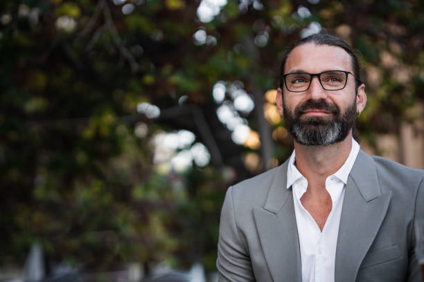 istock Confident businessman looking up with trees in background 2179029604