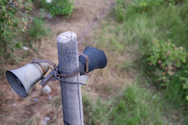 two vintage loudspeakers, one charred and abandoned on a concrete pole, symbolizing decay and nostalgia. It reflects the passage of time and forgotten technology