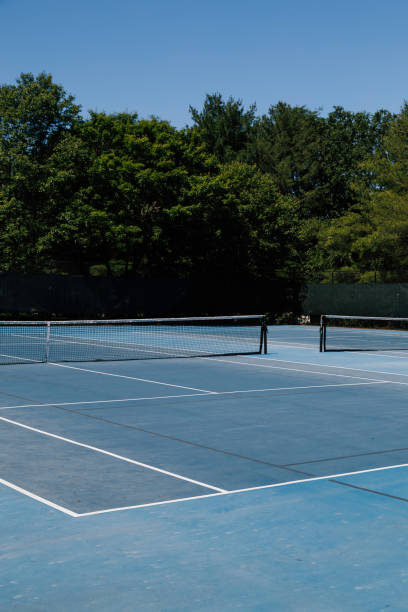 istock Empty Blue Tennis Court Surrounded By Trees Under Sunlight. 2179045538