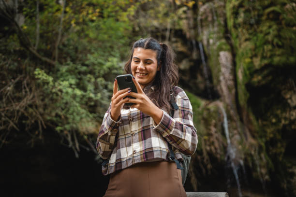 istock Beautiful woman hiker backpacker use mobile phone around waterfall 2179046015
