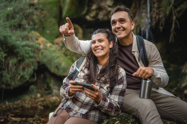 istock hugged hiker couple backpackers in front waterfall and use cellphone 2179046016