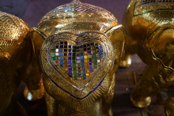 Golden elephant figurines on table, popular souvenir symbol of Thailand. Selective focus