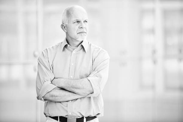 istock Senior manager looking away and thinking with arms crossed in of 2179071945