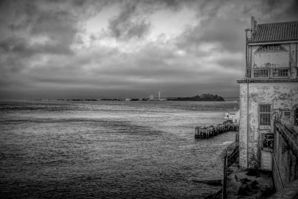 Dramatic seaside view of Alcatraz Island under a moody sky, showcasing its iconic architecture and historical significance in the heart of San Francisco Bay.