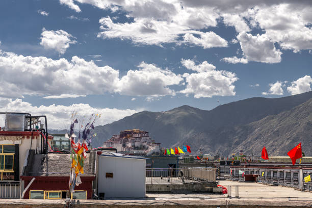 Bajiaojie, Lhasa, Tibet, China - May 21, 2022: Top angle view of flags on rooftop of a building against blue sky with window and white wall