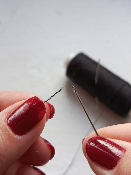 istock A woman's hands insert black thread into a sewing needle. Sewing and clothing repair. Hobby sewing. Background, space for text. Macro photo. 2179091246