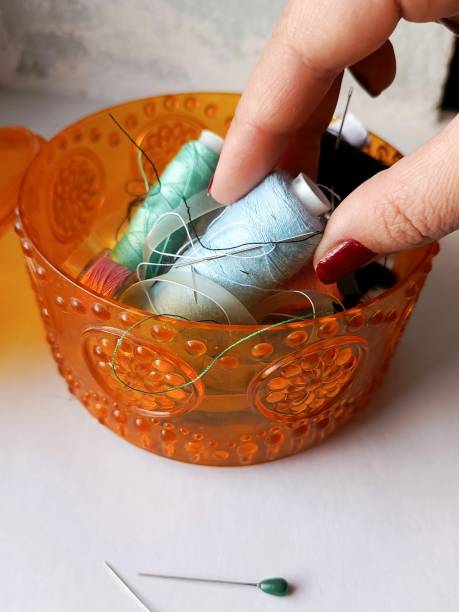 istock A woman's hand takes a spool of blue thread from a box with threads and needles. Sewing and clothing repair concept. Background, space for text. 2179091379