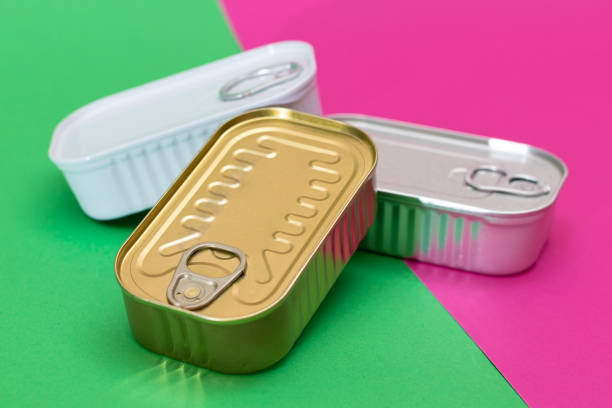 A Group of Stacked Tin Cans on Split Green and Cyan Background. Canned Food. Aluminum Cans for Safe and Long Term Storage of Food. Steel Sealed Food Storage Containers