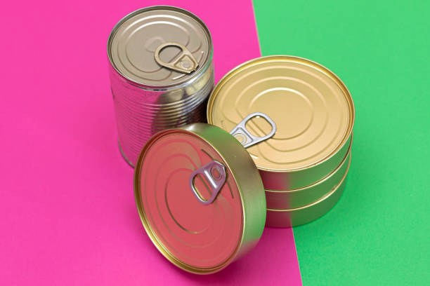A Group of Stacked Tin Cans on Split Green and Cyan Background. Canned Food. Aluminum Cans for Safe and Long Term Storage of Food. Steel Sealed Food Storage Containers