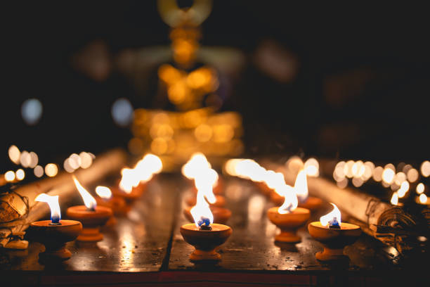 Lighting many candles in temples, religion, prayers and the concept of God. Close-up view of a burning flame on a candle isolated on black background.
