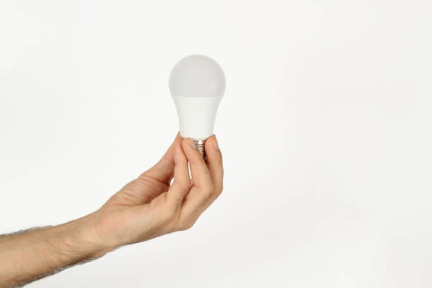 man holding a white light bulb isolated on white background. energy concept idea. - altin stok fotoğraflar ve resimler