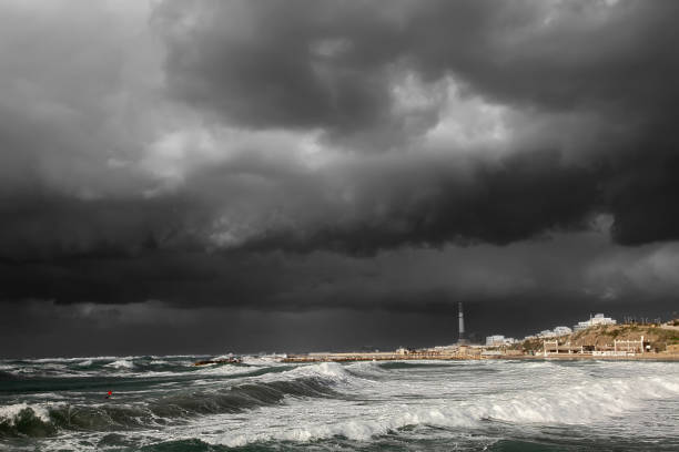 A lighthouse is silhouetted against a cloudy sky. The sky is dark and the lighthouse is the only light source