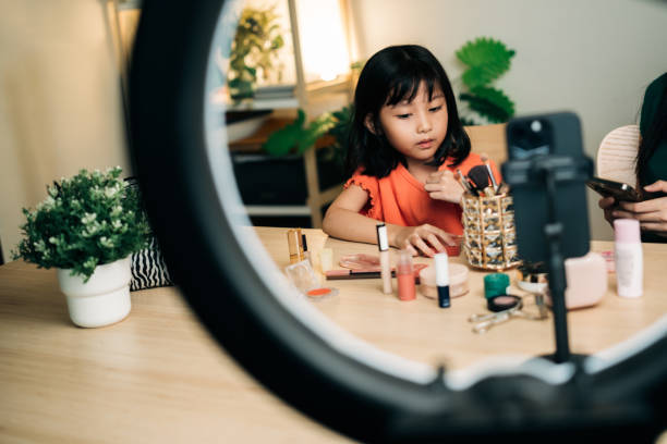 istock Mother and daughter doing makeup tutorial during live stream at home. Family-Centric Content 2179113085
