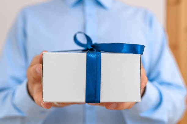 istock A birthday present in a cardboard box tied with a blue ribbon with a decorative bow. 2179113120