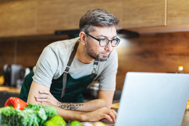 istock Mid adult man searching recipe in internet using laptop 2179115027