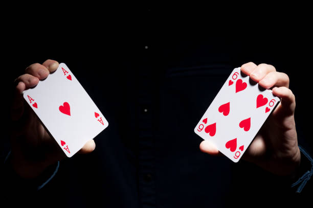 hands of illusionist showing play cards in the dark