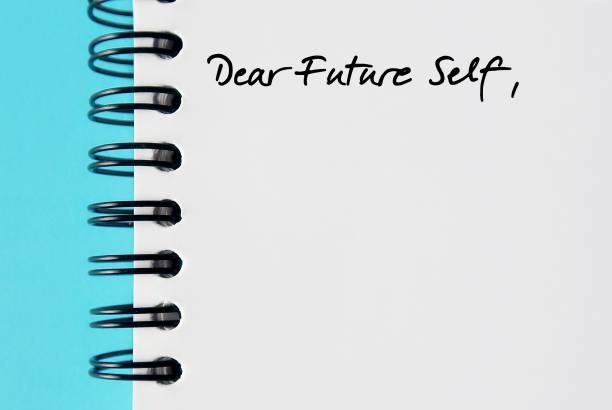 Notebook on blue background with handwritten text DEAR FUTURE SELF, a letter to convey message to future you. specific goals to achieve, follow up on bucket list items or declare important affirmation