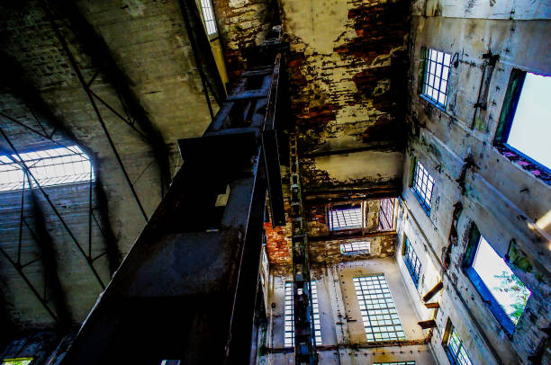 A large, empty building with a lot of windows. The building appears to be old and run down, with a lot of peeling paint and rust. Scene is somewhat eerie and abandoned